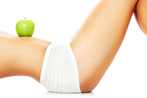A picture of a woman holding a green apple on her fit belly